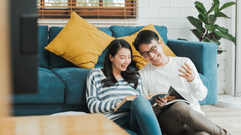 two people sitting on floor reading magazine together